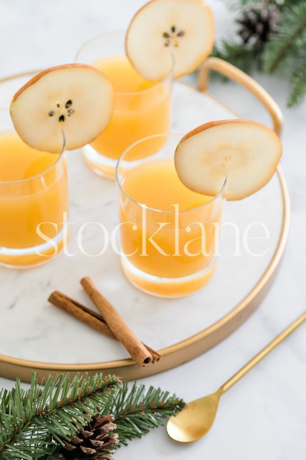 Vertical stock photo of a marble tray with pear cocktails and Christmas decor.