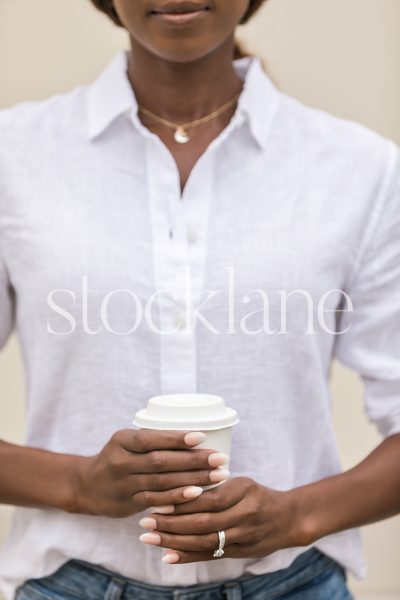 Vertical stock photo of a woman holding a cup of coffee.