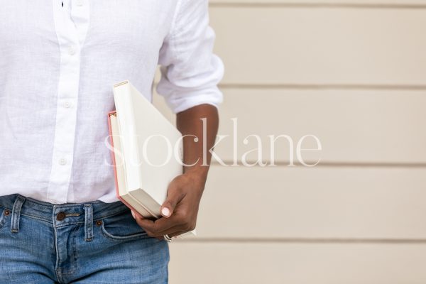 Horizontal stock photo of a woman holding a stack of books.