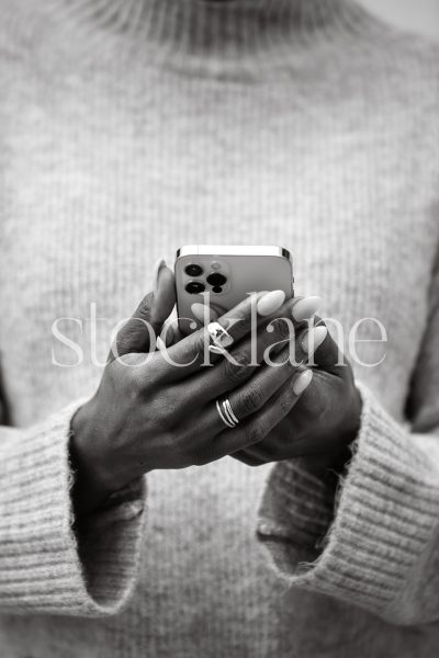 Vertical black and white photo of a woman holding a phone.