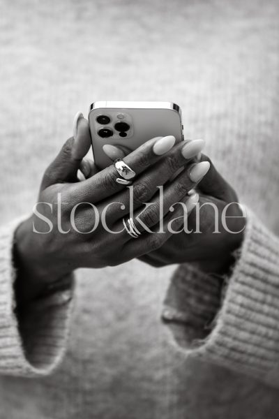 Vertical black and white photo of a woman holding a phone.