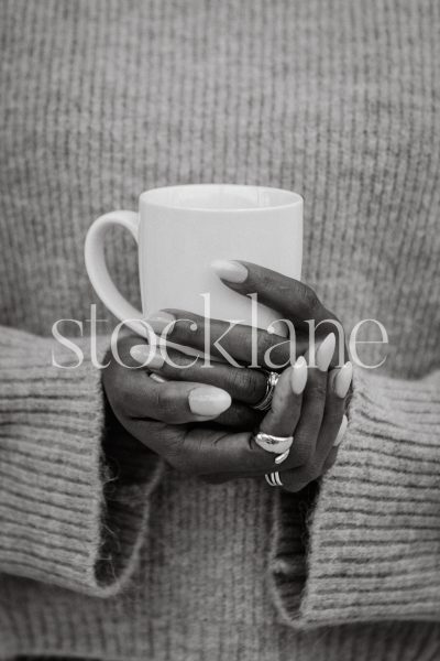 Vertical stock photo of a woman's hands holding a cup of coffee.