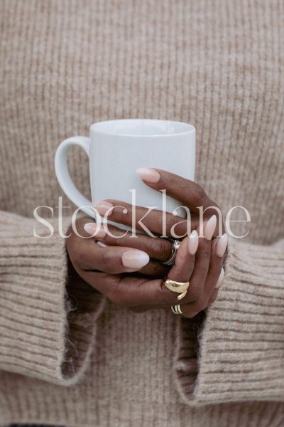 Vertical stock photo of a woman's hands holding a cup of coffee.