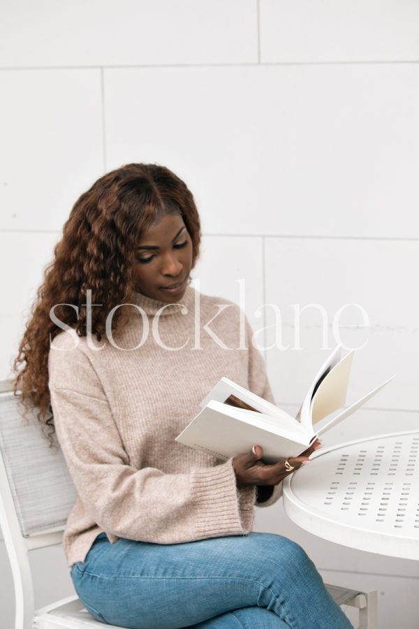 Vertical stock photo of a woman reading a book.