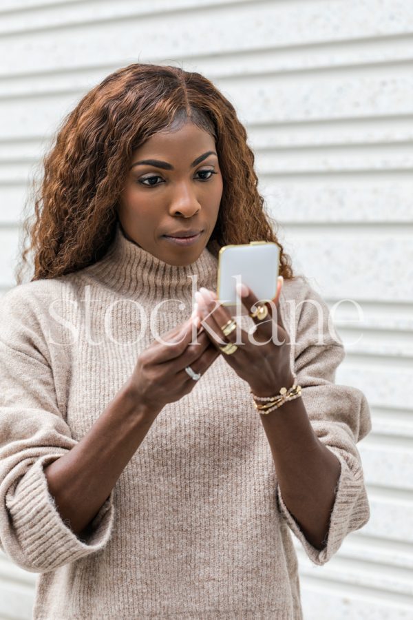 Vertical stock photo of a woman holding a makeup compact case.