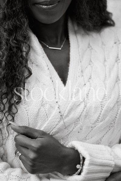 Vertical black and white stock photo of a woman wearing a chunky knit white sweater.