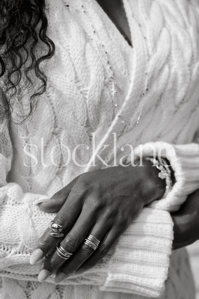 Vertical black and white stock photo of a woman wearing a chunky knit white sweater.