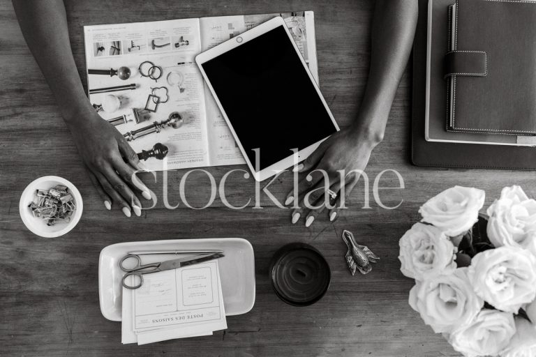 Horizontal black and white photo of a woman's hands over her work desk.