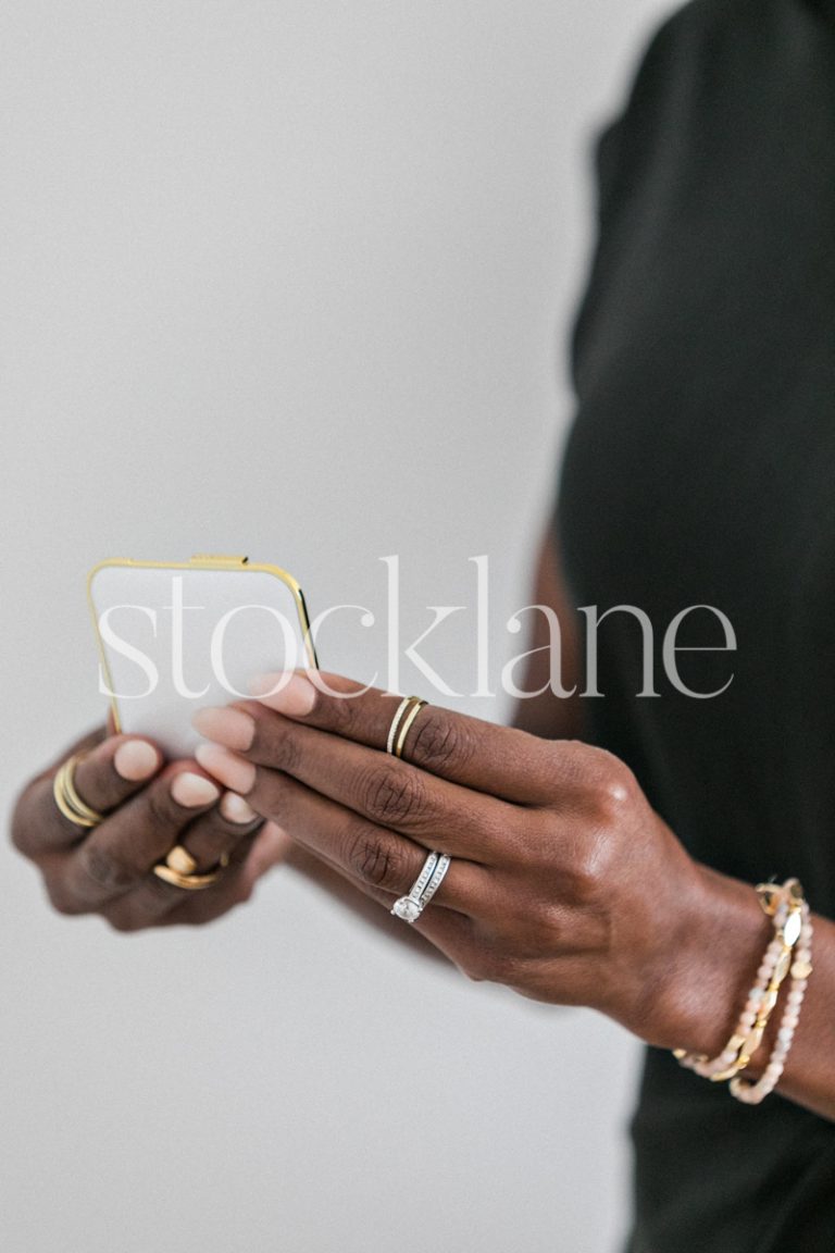 Vertical stock photo of a woman holding a compact makeup kit.