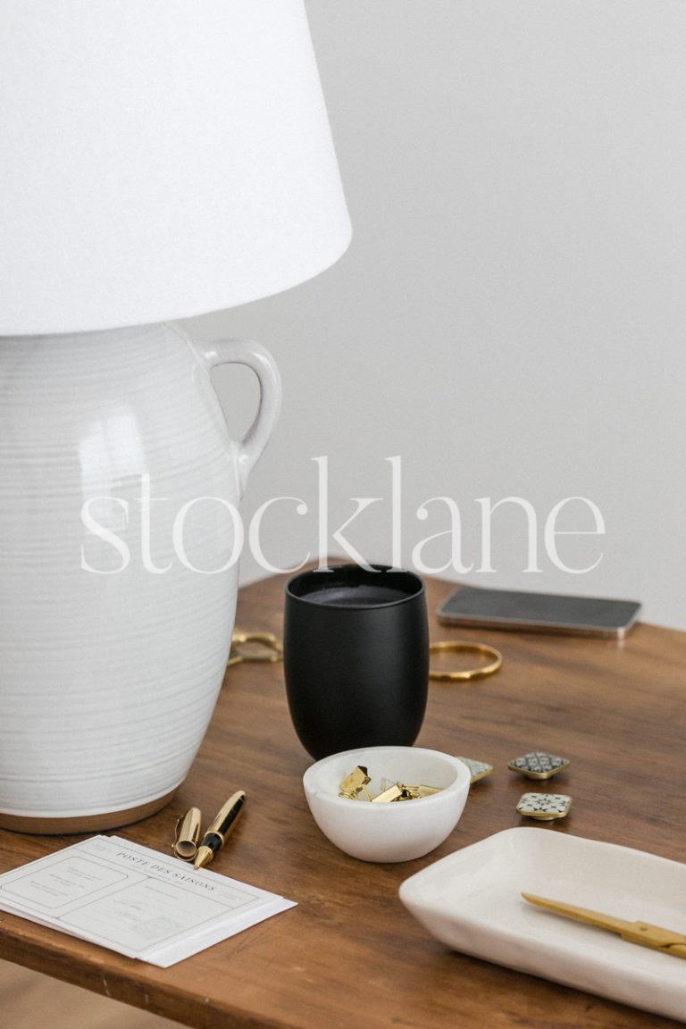 Vertical stock photo of a desk with white gold and black decor and work items.