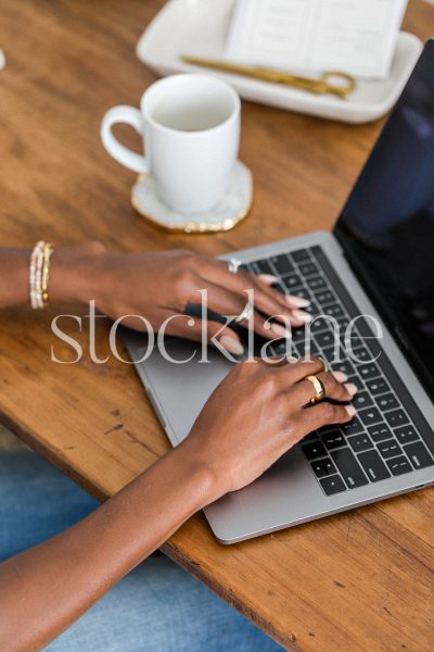 Vertical stock photo of a woman sitting at her desk working on her laptop computer.