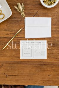 Vertical stock photo of stationery and gold pen on a desk.