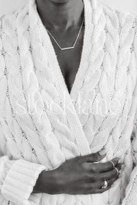 Vertical black and white stock photo of a woman wearing a chunky white sweater.