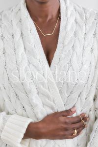 Vertical stock photo of a woman wearing a chunky white sweater.