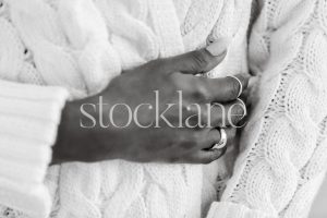 Horizontal black and white stock photo of a woman wearing a chunky white sweater.
