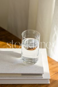 Vertical stock photo of a glass of water on top of books.