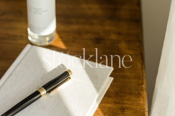 Horizontal stock photo of a notebook and a black pen on a wood table.