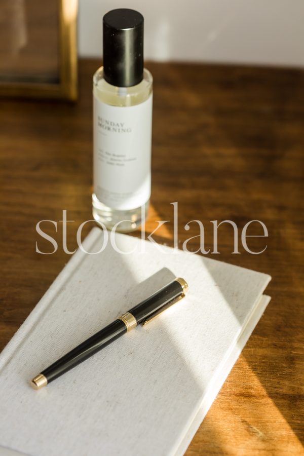 Vertical stock photo of a notebook and a black pen on a wood table.