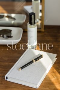 Vertical stock photo of a notebook and a black pen on a wood table.