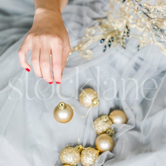 Vertical stock photo of a woman in a light blue dress with Christmas ornaments